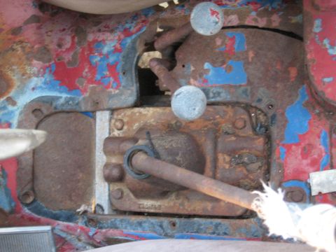 1983 Chevrolet Silverado 1500 - Close-up of heavily rusted mechanical parts, possibly from a tractor or older vehicle, with visible shift levers.