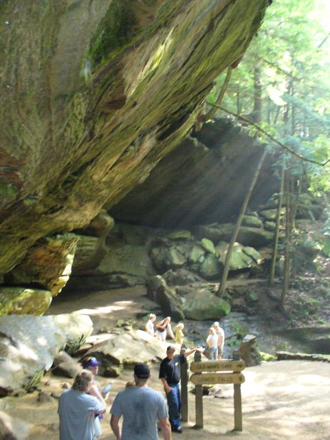 1991 Ford Probe - A group of people explore a natural rock formation and wooded trail, with a sign indicating nearby attractions.