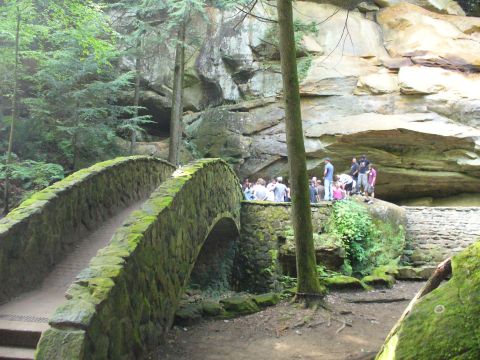 1991 Ford Probe - A group of people are gathered near a moss-covered stone bridge and a large rock formation.