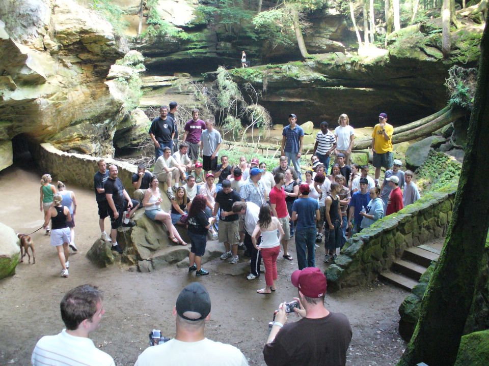 Group of people gathered in a rocky canyon with trees and a wooden staircase