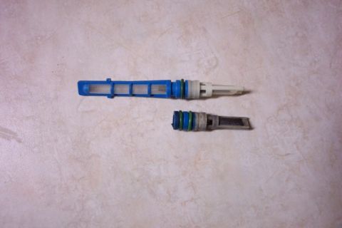 1992 Ford Bronco - Two AC Schrader valve cores are shown, one new and one used, on a light-colored textured background.