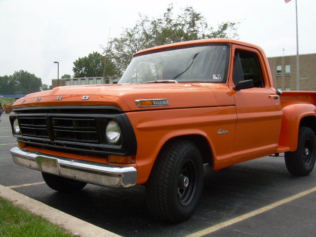 Orange Ford stepside pickup truck parked in a lot
