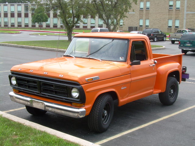 Orange Ford stepside pickup parked in a parking lot