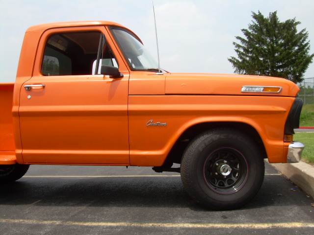 Side view of an orange Ford Custom stepside pickup truck