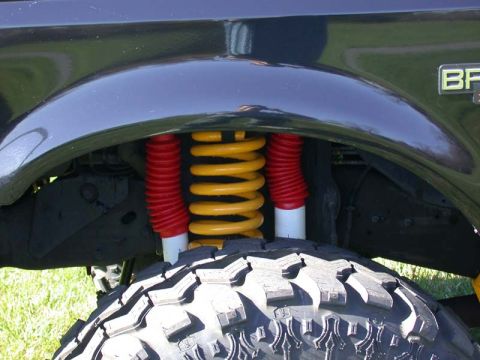 1996 Ford Bronco - Close-up of the suspension system on a 1996 Ford Bronco, highlighting the yellow coil spring and red shock absorber boots.