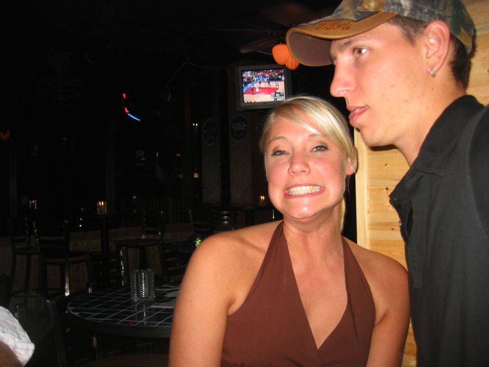Two people posing inside a dimly lit bar