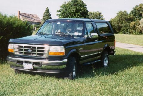 1996 Ford Bronco - This black Ford Bronco is shown from the front-three-quarter view, parked on a grassy lawn.