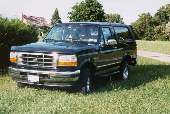 Black Ford Bronco on lawn, front three-quarter view showing chrome grille and Ford oval