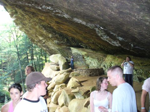 1991 Ford Probe - A group of people stand in a cave-like formation with a large rock overhang and surrounding trees.