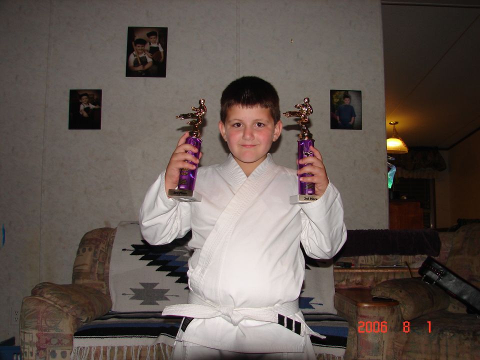 kid in karate gi holding two trophies