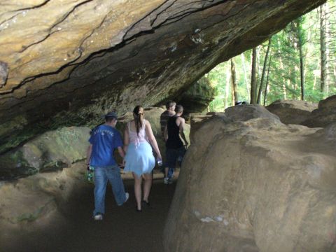 1991 Ford Probe - Hikers explore a natural cave formation with trees visible beyond the entrance.