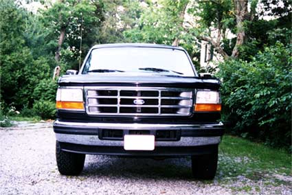 1996 Ford Bronco - Front view of a 1996 Ford Bronco parked outdoors with trees in the background.
