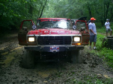 1979 Ford Bronco - Red 1979 Ford Bronco is stuck in the mud with its doors open.