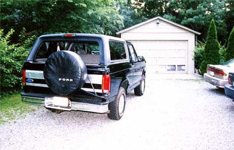 1996 Ford Bronco - A black Ford Bronco is parked in a gravel driveway in front of a detached garage.