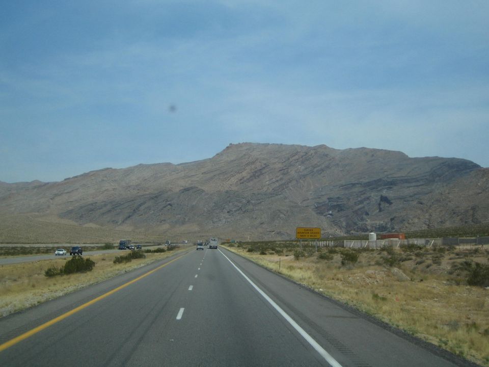 Desert interstate highway leading toward a barren mountain ridge