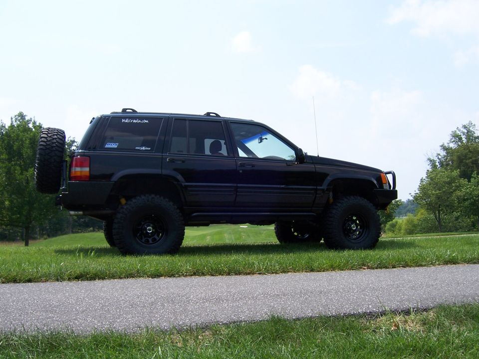 Lifted black Jeep Grand Cherokee ZJ side view on mud tires with rear tire carrier