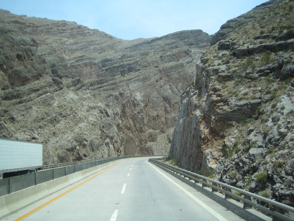 Highway cutting between towering steep rock canyon walls with a box truck
