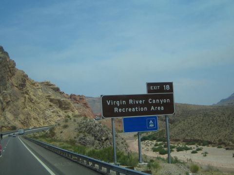 1990 Ford Bronco - brown freeway sign for Virgin River Canyon Recreation Area Exit 18 stands beside a desert highway.