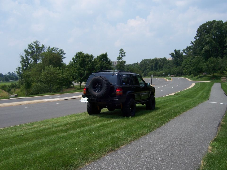 Black lifted Jeep Grand Cherokee ZJ, rear three-quarter view, with rear spare-tire carrier