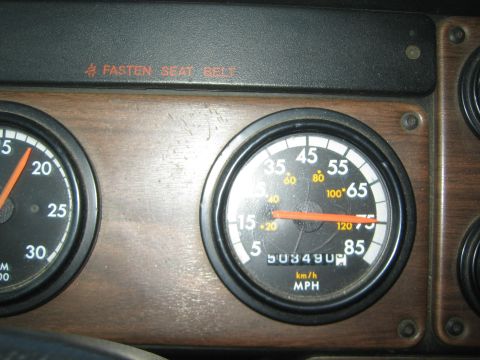 1990 Ford Bronco - wood-trim dashboard shows a tachometer and MPH speedometer with odometer reading near 503490 and Fasten Seat Belt light.
