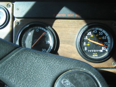 1990 Ford Bronco - wood-trim truck dash shows the tachometer and MPH speedometer with the steering wheel rim in the foreground.