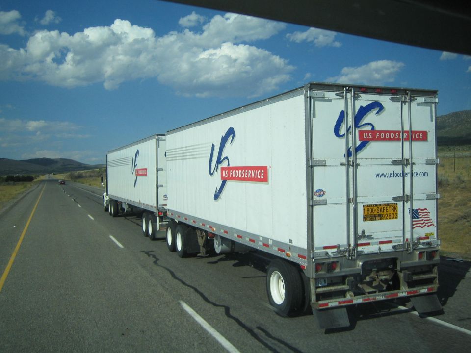 U.S. Foodservice double-trailer semi truck on a highway under puffy clouds