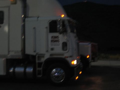 1990 Ford Bronco - white cabover semi tractor sits in a dark lot at night with amber marker lights glowing.