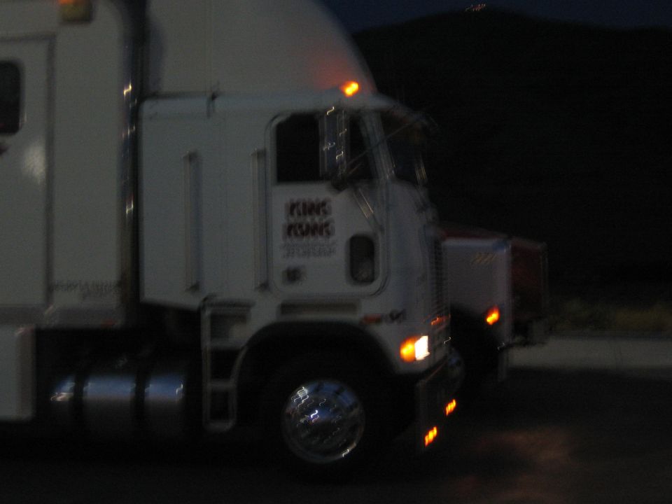 white cabover semi truck parked at night with running lights on