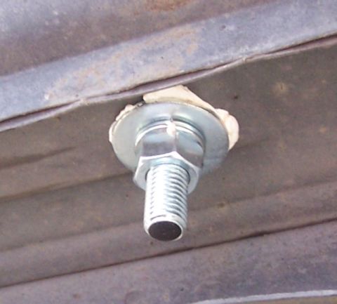 1990 Ford Bronco - A single bolt with a washer and nut is attached to a ribbed metal surface, likely for tie-down purposes.