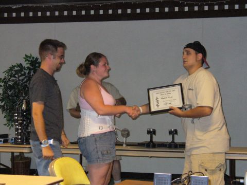 1991 Ford Probe - People are gathered for an award ceremony, with one individual receiving a certificate and a mechanical component.