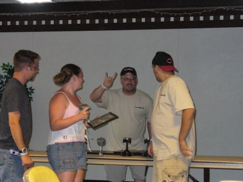 1991 Ford Probe - Four people are gathered around a table displaying trophies, possibly at an awards ceremony or event.