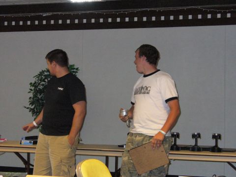 1991 Ford Probe - Two men are seen in a room with tables displaying engine parts and a clipboard on one of the tables.
