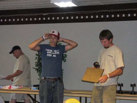 1991 Ford Probe - Three men are gathered indoors, possibly at a competition or awards ceremony, with one man wearing a humorous t-shirt.