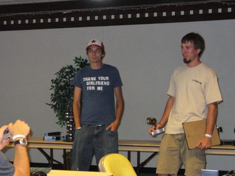 1991 Ford Probe - Two men stand indoors, one holding a trophy and clipboard, the other wearing a graphic t-shirt.