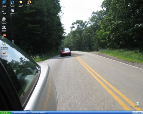 1991 Ford Probe - Windows XP desktop screenshot whose wallpaper is a rolling shot taken alongside a silver car, following a red hatchback coupe down a double…