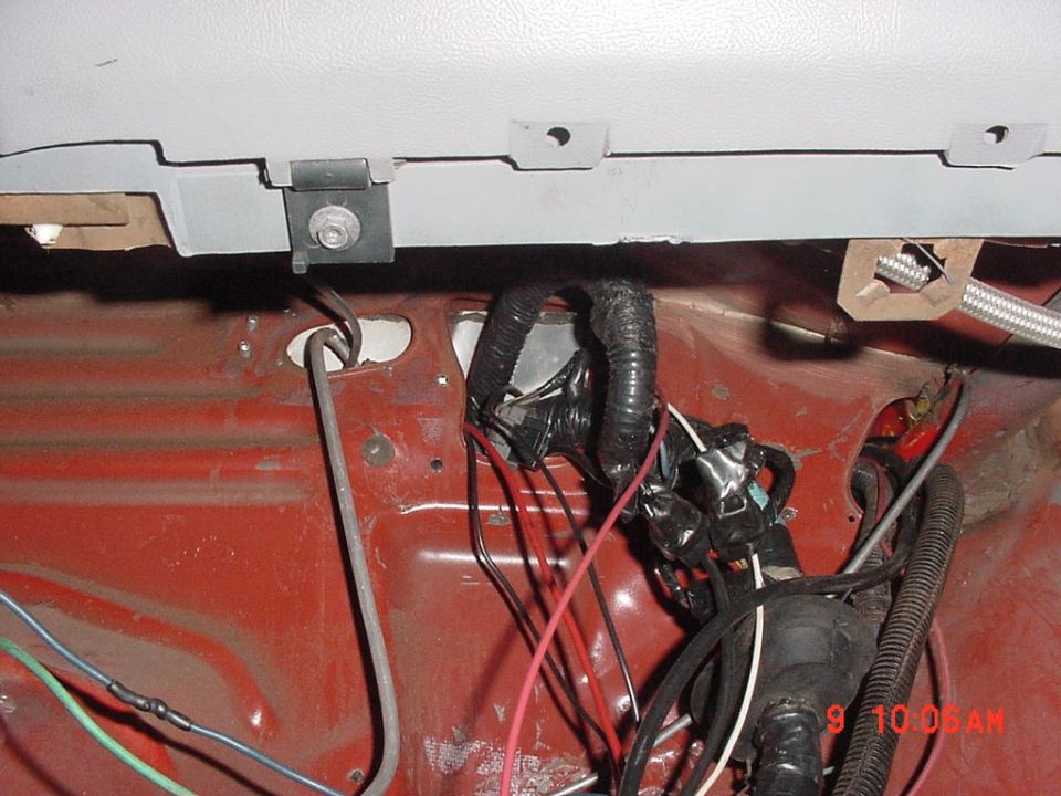 Vehicle interior wiring harness with red and black wires, taped bundles, and metal brackets. Timestamp 9 10 06 AM visible