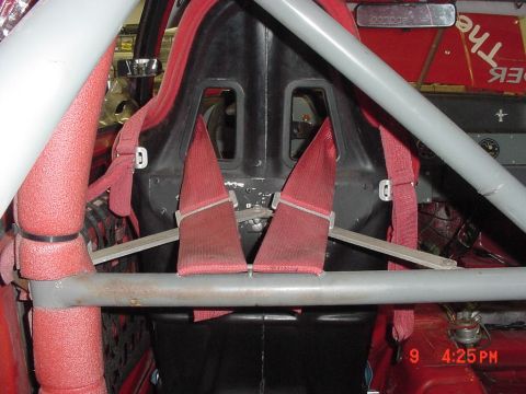 1993 Ford Mustang - Interior view of a racing seat with a red harness and roll cage structure.