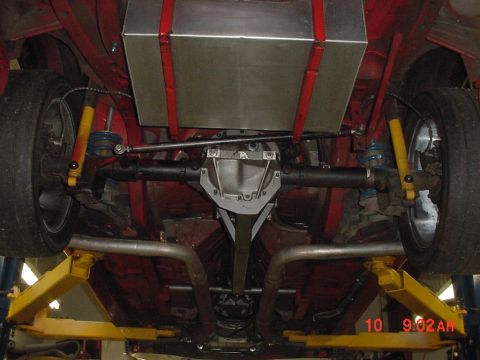 1993 Ford Mustang - Undercarriage view shows the rear suspension, fuel tank, and dual exhaust system of a red vehicle.