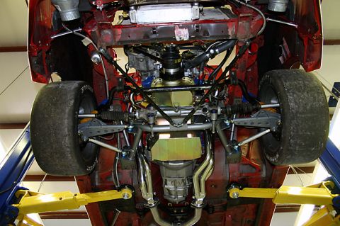 1993 Ford Mustang - The underside of a red vehicle is visible, with its suspension and engine components exposed.