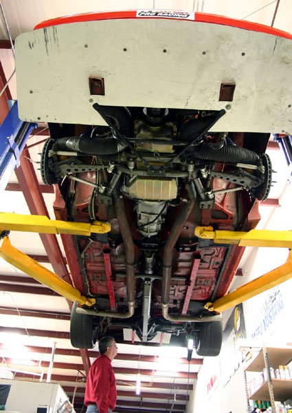 1993 Ford Mustang - A mechanic inspects the undercarriage of a vehicle suspended on a lift in a workshop.