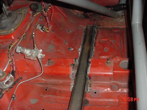 1993 Ford Mustang - Interior view of a red car undergoing modifications, a roll cage and exposed brake lines.