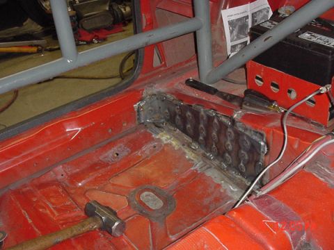 1993 Ford Mustang - The interior floor of a car is shown with freshly welded metal patches and a roll cage installed.