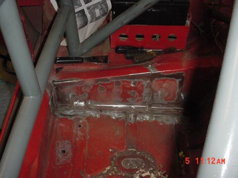 1993 Ford Mustang - The interior floor of a car shows signs of rust repair and a roll cage, with tools visible on the dashboard.