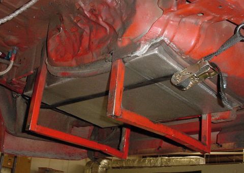 1993 Ford Mustang - Custom metal bracing and fuel lines are visible on the underbody of a red vehicle, suggesting modifications or repairs.