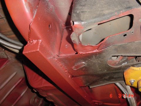 1993 Ford Mustang - Close-up view of the undercarriage of a red vehicle, showing structural components and brake lines.
