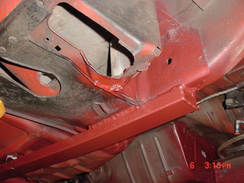1993 Ford Mustang - The underside of a vehicle shows a mix of old rust and new red paint on its frame and body panels.