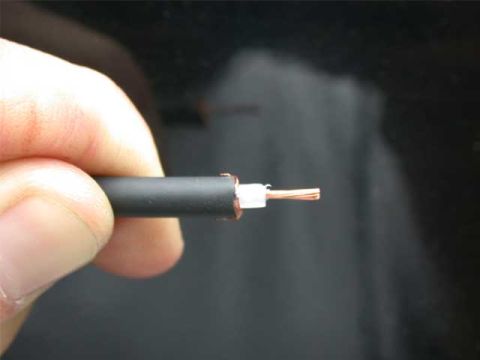 1996 Ford Bronco - A hand holds the stripped end of a black coaxial antenna cable, showing the copper braid shield folded back over the white dielectric with…