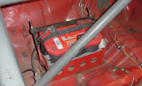 1993 Ford Mustang - The trunk of a car shows a red Optima battery mounted in a custom red bracket, with a roll cage present.