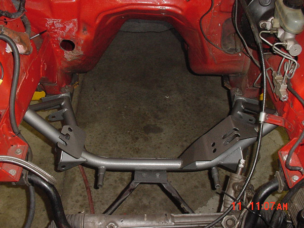 Red engine bay frame with gray metal bracing and brake lines. Some rust visible