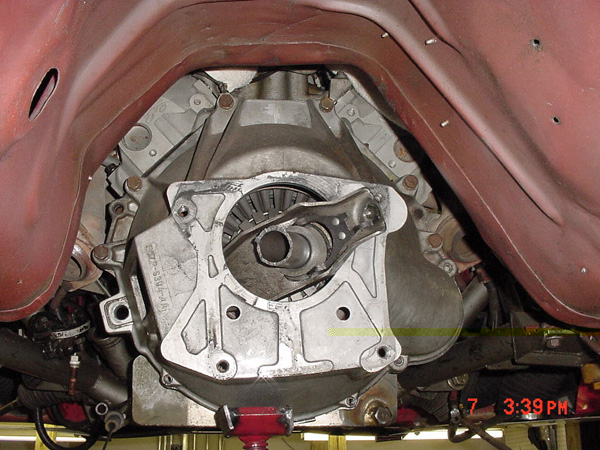Close-up of a car's transmission bell housing, showing the clutch fork and pressure plate assembly